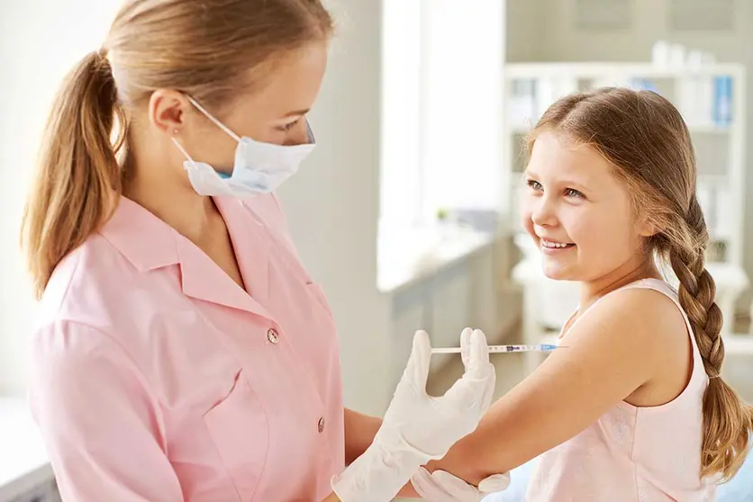 Adorable girl looking at nurse while she making her an injection in clinics